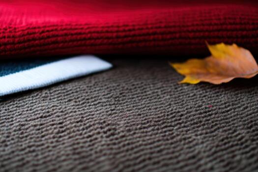 Warm textures of autumn fabrics and a falling leaf on a cozy surface photo
