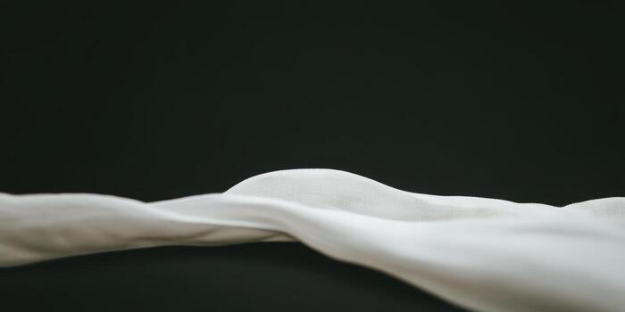 Soft white fabric draped gracefully on a dark surface creating elegant curves photo