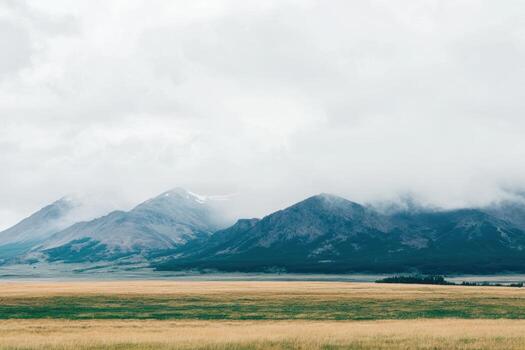 Cloudy mountain landscape with grassy field in the foreground during spring photo