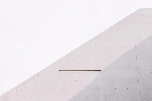 Minimalist architecture showcasing angled concrete wall against clear sky photo