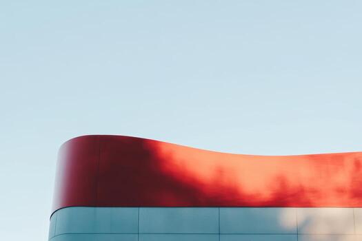 Modern building with curved architecture and vivid red accents in clear sky photo