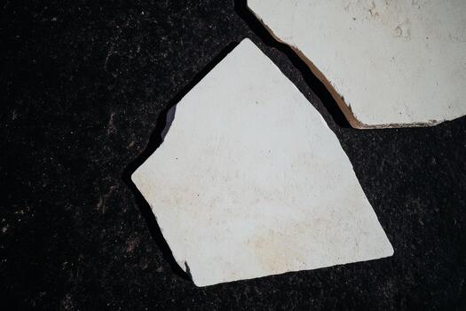 White stone fragments lying on a dark surface during daylight hours photo