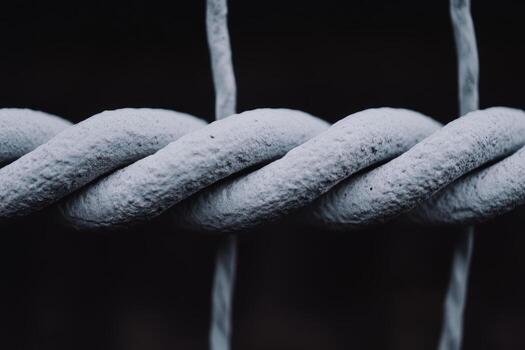 Close-up view of textured gray rope twisting against a dark background photo