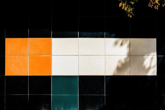 Colorful tiled wall with shadow patterns in urban setting during daylight photo
