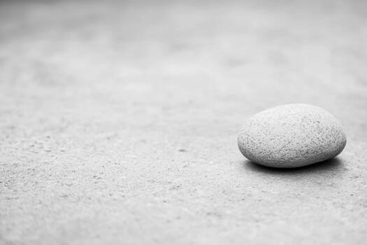 Smooth stone rests on a textured surface in black and white setting photo