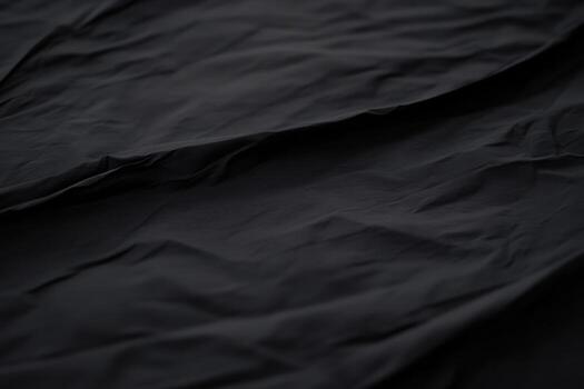 Textured black fabric with subtle folds and shadows captured in close-up photo