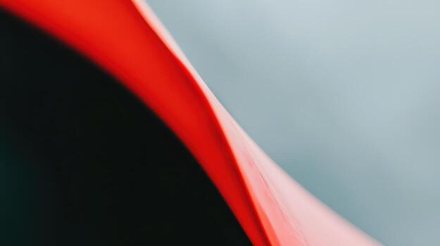 Close-up of a curved, vibrant red surface against a soft gray backdrop photo