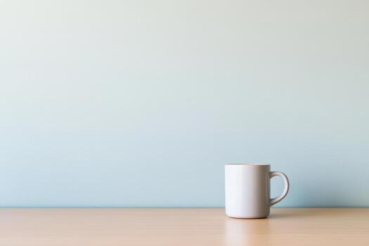 Simple white mug on a wooden table with a soft blue background photo