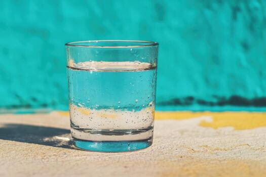 Clear glass of sparkling water on a colorful background in sunlight photo