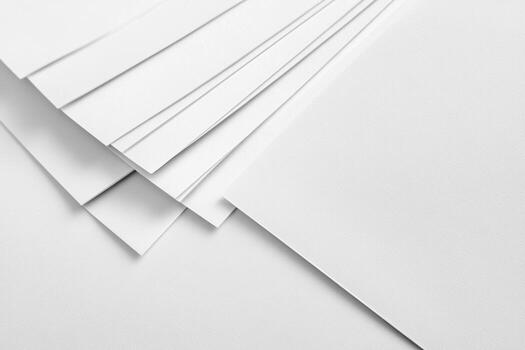 White sheets of paper stacked neatly on a flat surface in natural light photo