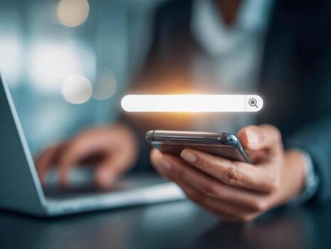 Businessman using smartphone with laptop in background and illuminated digital search bar icon representing online information and data retrieval concepts photo