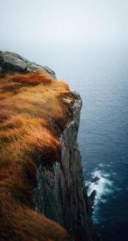 A cliff with grass and water in the background photo