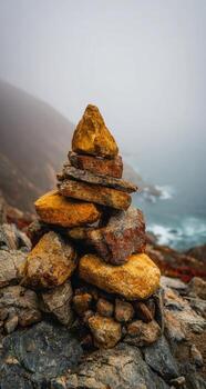 A stack of rocks on top of a mountain overlooking the ocean photo