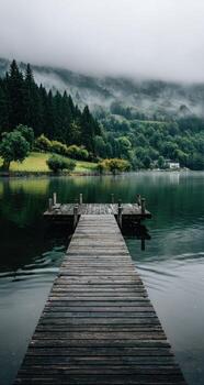A wooden dock extends into the water on a foggy day photo