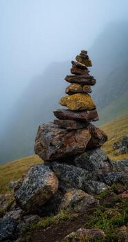 A stack of rocks on a hill in the fog photo