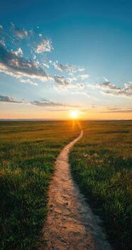 A dirt path in the middle of a grassy field at sunset photo