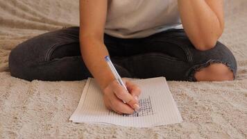 uma mulher meticulosamente resolve sudoku quebra-cabeças em gráfico papel, sentado confortavelmente em uma suave superfície. ela concentrados atentamente, caneta dentro mão, desfrutando uma pacífico momento do mental desafio video
