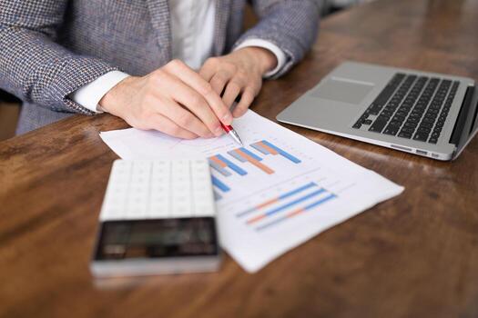 a businessman follows a sales chart in the form of columns on a table next to a laptop and a calculator photo