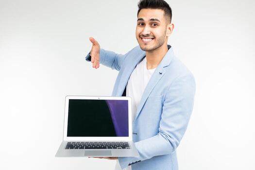 stylish man in a blue jacket shows a laptop display with a blank template for inserting a site on a white studio background photo