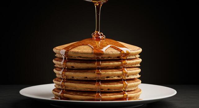 Golden Pancakes Stacked on Plate with Syrup Pouring Against Black Background photo