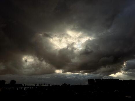 The sun is being covered by dark clouds.. The sun is shining through the clouds. photo