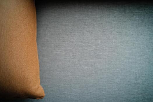 Warm brown pillow rests against a soft blue fabric surface in a cozy setting photo