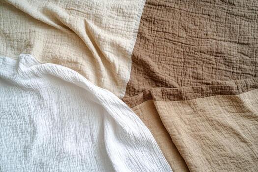 Soft cotton fabric in neutral tones displayed on a bed quilt photo