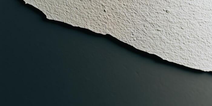 A close-up view of a torn piece of white paper resting against a dark surface photo