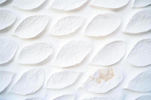 Unique white textured wall with leaf-shaped patterns in sunlight photo