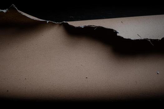 Torn paper revealing textured surface in low light setting photo