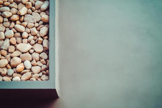Decorative stones in a modern planter against a smooth wall photo