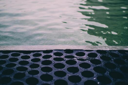 Water surface reflects light near black grate in serene setting photo
