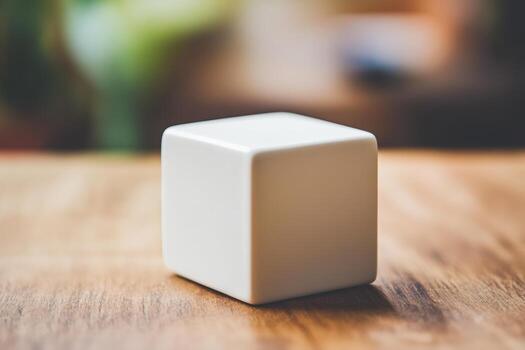 Simple white cube on wooden surface with blurred background photo