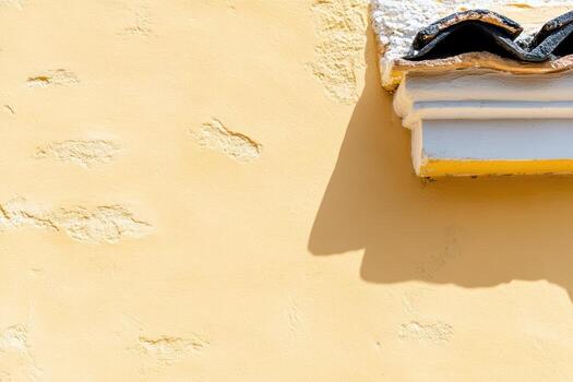 Bright yellow wall texture with a decorative ledge and shadow play photo