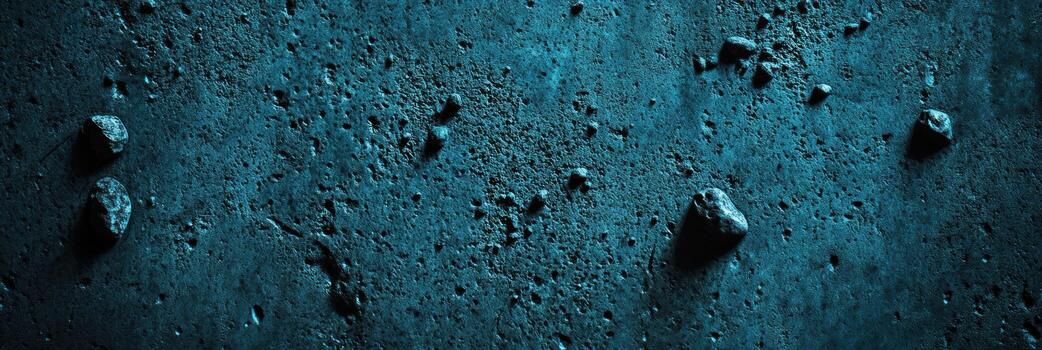 Textured surface with scattered stones under dim blue light in a dark setting photo