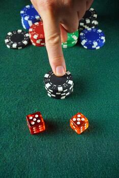 Two dice with fives in a dice game on a green table. The player's finger points to the chips for the winning bet photo