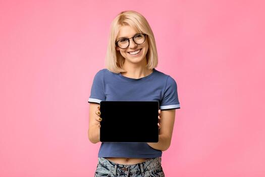 Cool application. Happy lady showing tablet computer with empty screen to camera, recommending new app. Woman posing over studio background. Digital tablet display mockup for advertisement photo