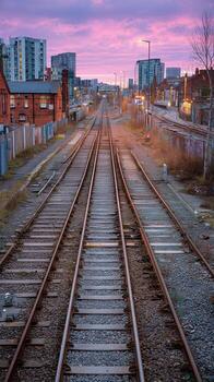 Tranquil Railway Tracks Under Pink Sunset in Urban Setting photo