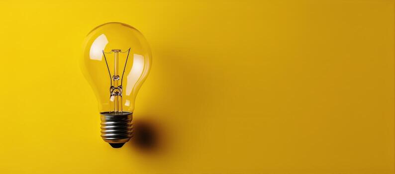 Incandescent Lightbulb Sits on Bright Yellow Background Providing Space for Text photo