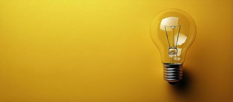 Incandescent Lightbulb Sits on Bright Yellow Background Providing Space for Text. photo