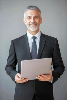 Professional Man in a Suit Holding a Laptop With a Confident Smile in a Modern Office Setting photo