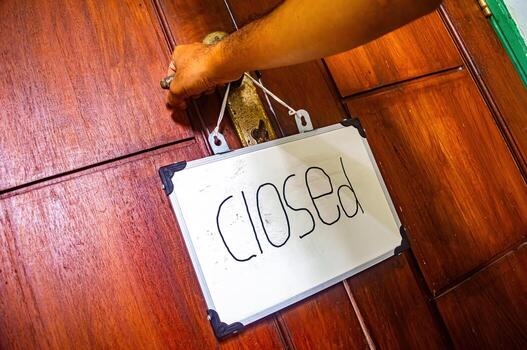 Hand turning door handle with hanging closed sign on whiteboard, symbolizing transition, boundaries, and mindful pause in personal or work space photo