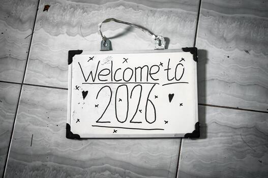 Handwritten Welcome to 2026 sign with hearts and X marks placed on marble tile floor, symbolizing new year joy, fresh starts, and personal reflection photo