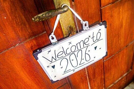 White Welcome to 2026 sign with hearts and stars hanging from door handle, symbolizing new year joy, fresh starts, and hopeful transitions. photo