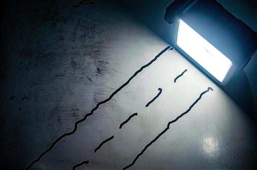 Diagonal black streaks on worn white surface lit by bright light evoking raw emotion, imperfection, and abstract tension in a minimalist, high contrast composition photo