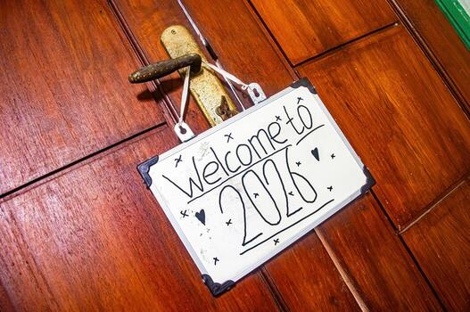 Handwritten Welcome to 2020 sign with heart and star doodles hanging on aged door handle, symbolizing new beginnings, hope, and personal warmth. photo