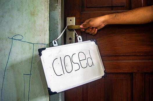 Hand holding door handle with hanging closed sign, symbolizing boundaries, pause, and personal space in a quiet, mindful setting photo