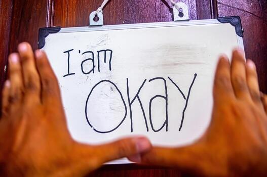 Framed hands highlight a whiteboard with I am Okay message, symbolizing self acceptance, mental health awareness, and emotional resilience photo