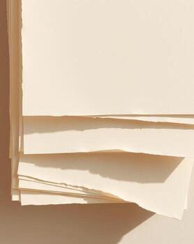 A stack of cream-colored paper sheets with a rough, torn edge, creating shadows and texture. photo
