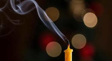 extinguido vela con creciente fumar en bokeh antecedentes foto